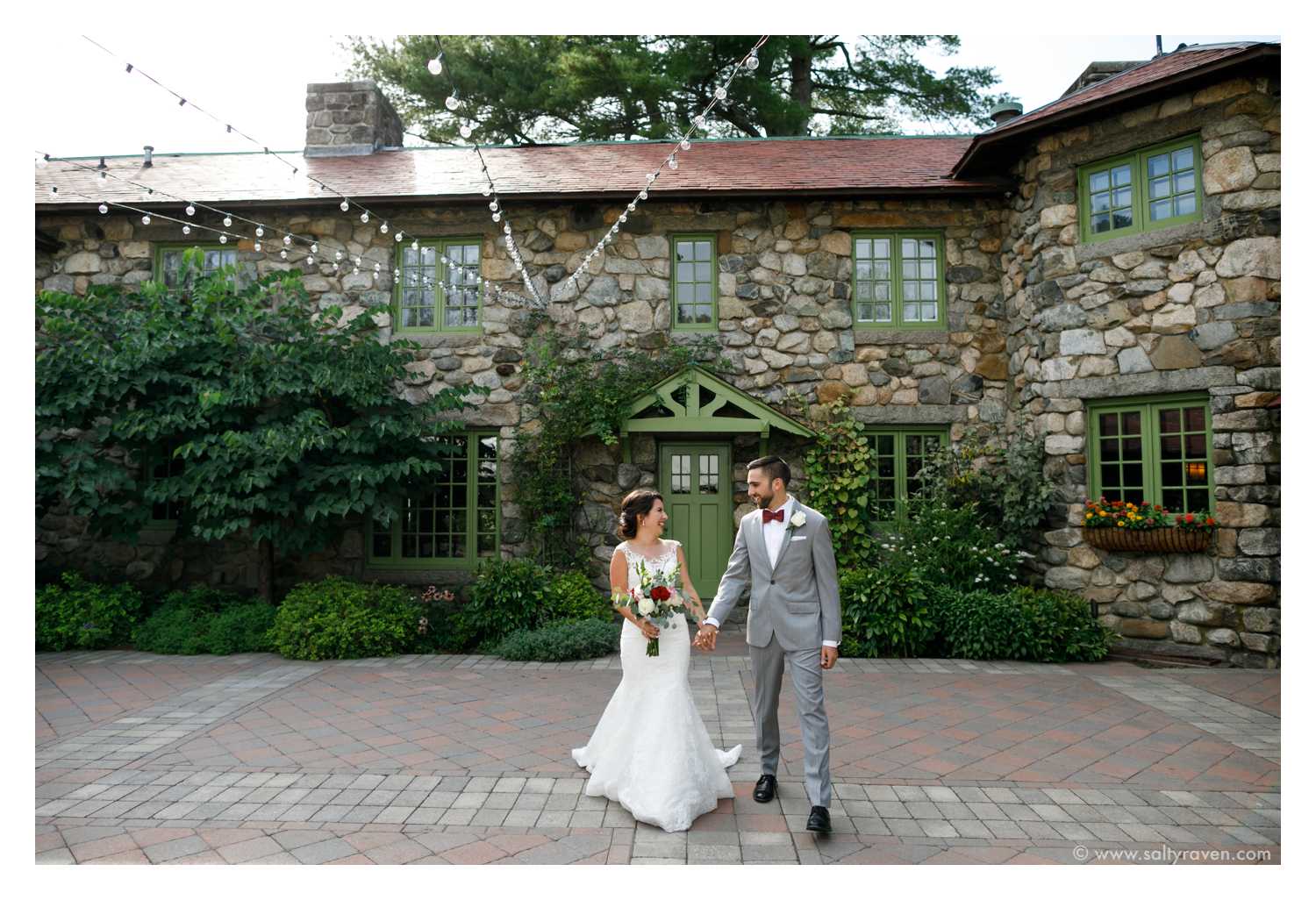 Willowdale Estate Wedding, couple walks hand in hand in front of stone building.