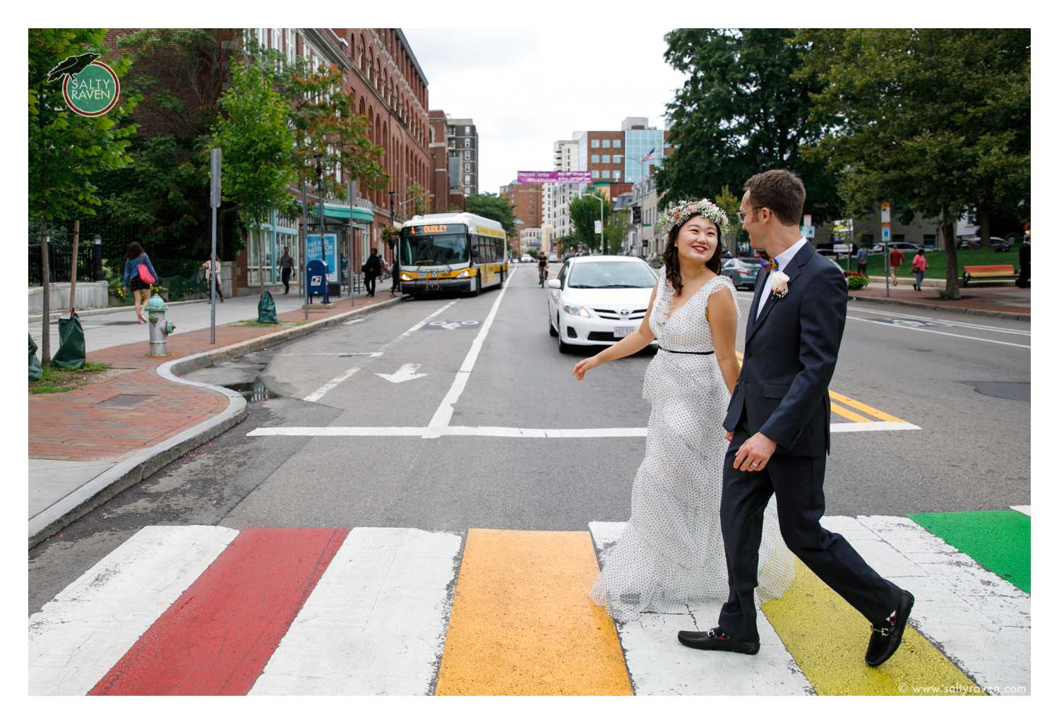 A couple getting married at Cambridge City Hall crosses a rainbow crosswalk.